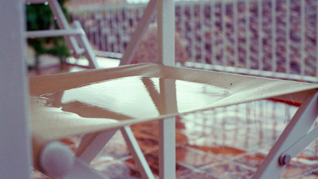 Close-up of an empty chair with water on the seat.