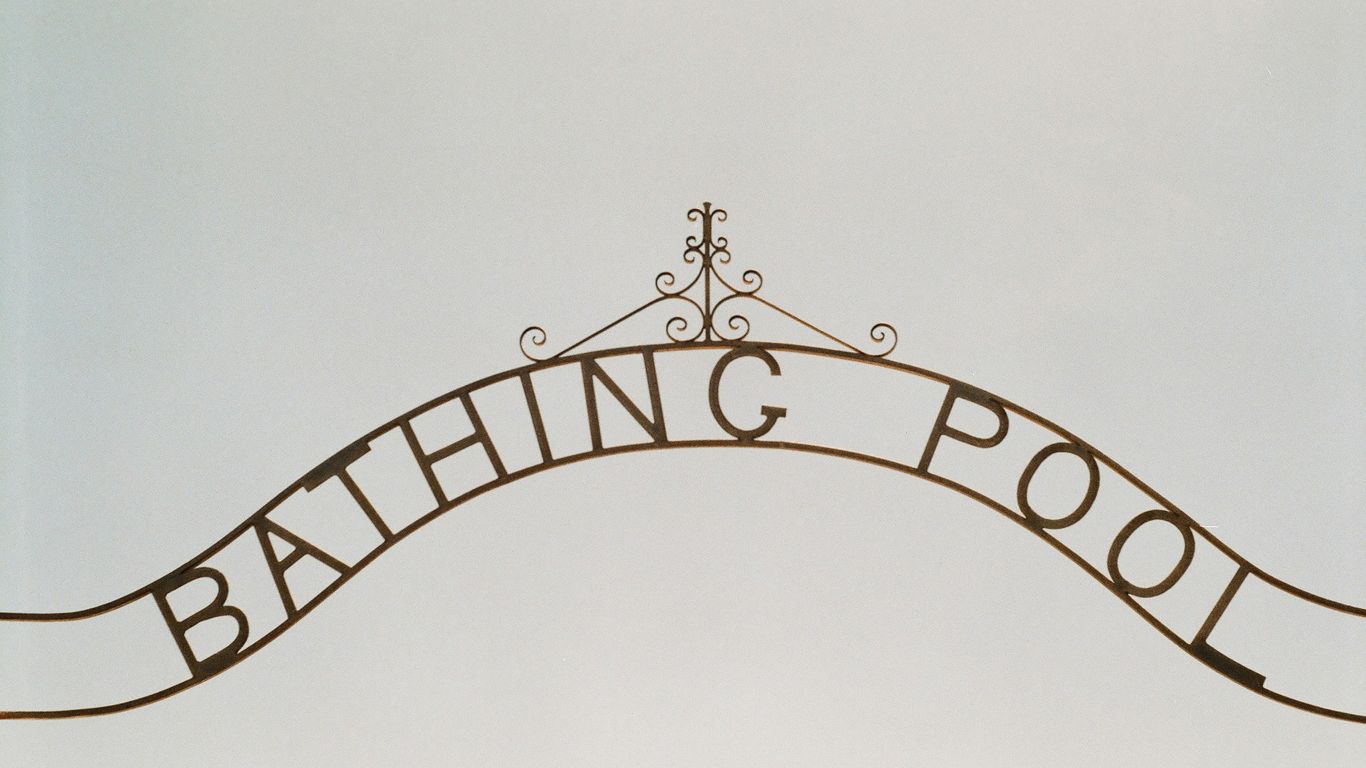 A sign that says bathing pool hanging from the side of a building