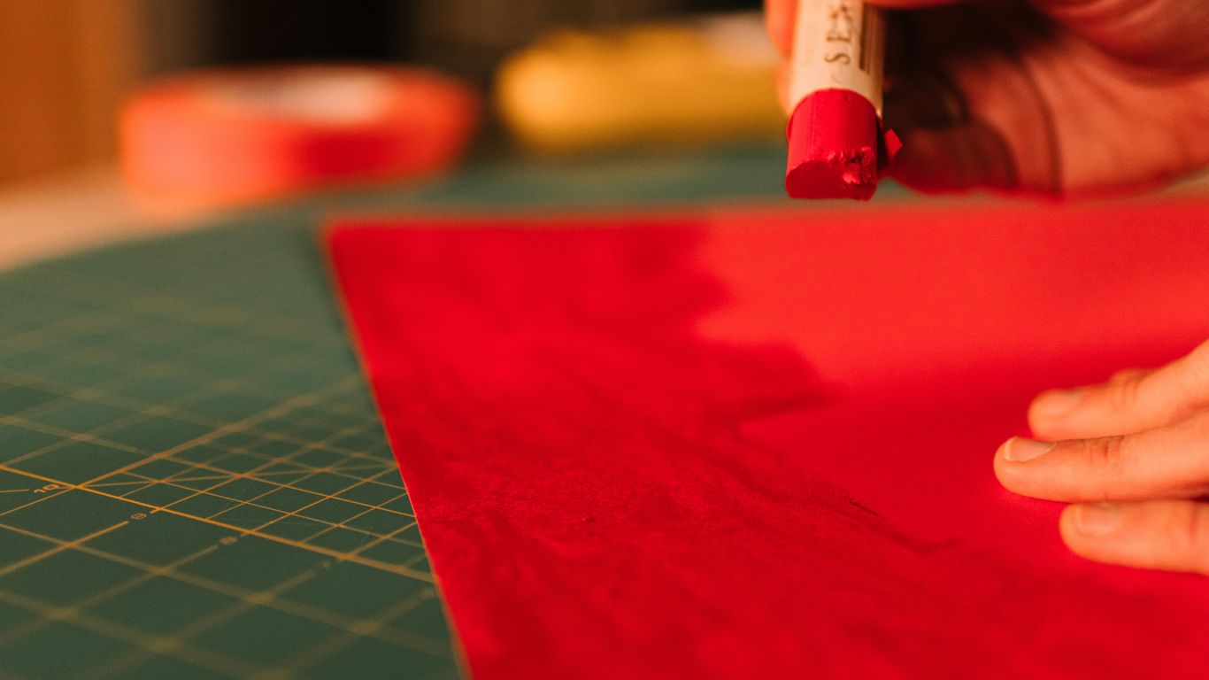 Hand applying glue stick to red paper.